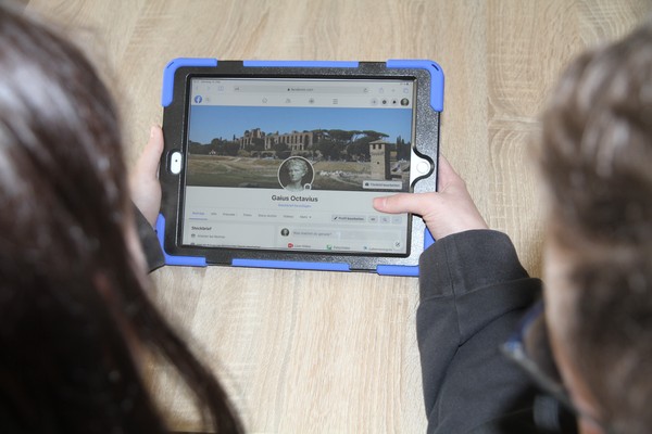 Foto: Zwei Jugendliche schauen sich mit einem tablet das Facebookprofil eines römischen Caesaren an.