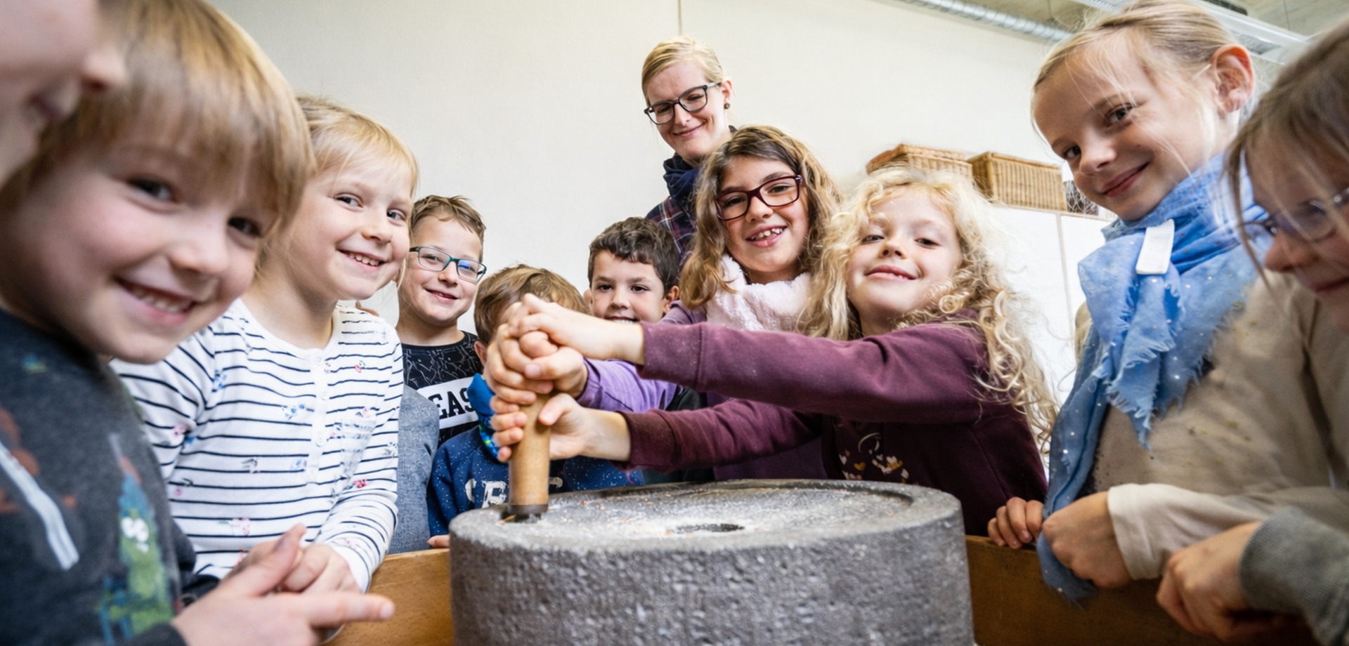 Kinder beim Mehl mahlen mit römischer Handmühle