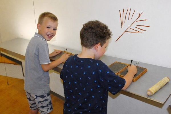 Foto: Zwei Jungen ritzen in römische Wachstafeln.