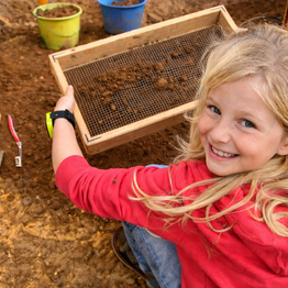 Ein Mädchen siebt Erde.